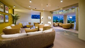 A spacious lobby with wicker furniture, a large plant, and framed pictures on the walls. - Hotel Europa (San Michele al Tagliamento)