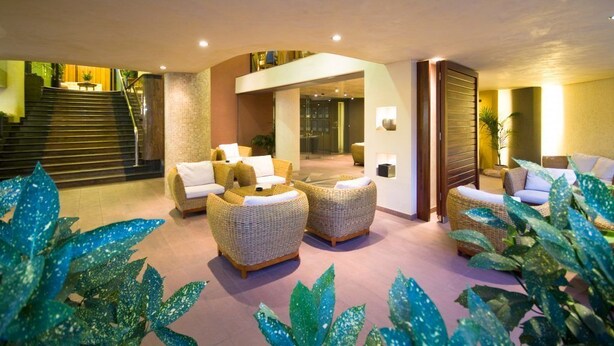 A lobby with wicker furniture, a staircase, and a view of the interior. - Hotel Europa (San Michele al Tagliamento)