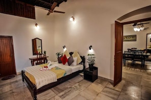 Quarto com cama de madeira, mesas de cabeceira, ventoinha no teto e luminárias na parede.