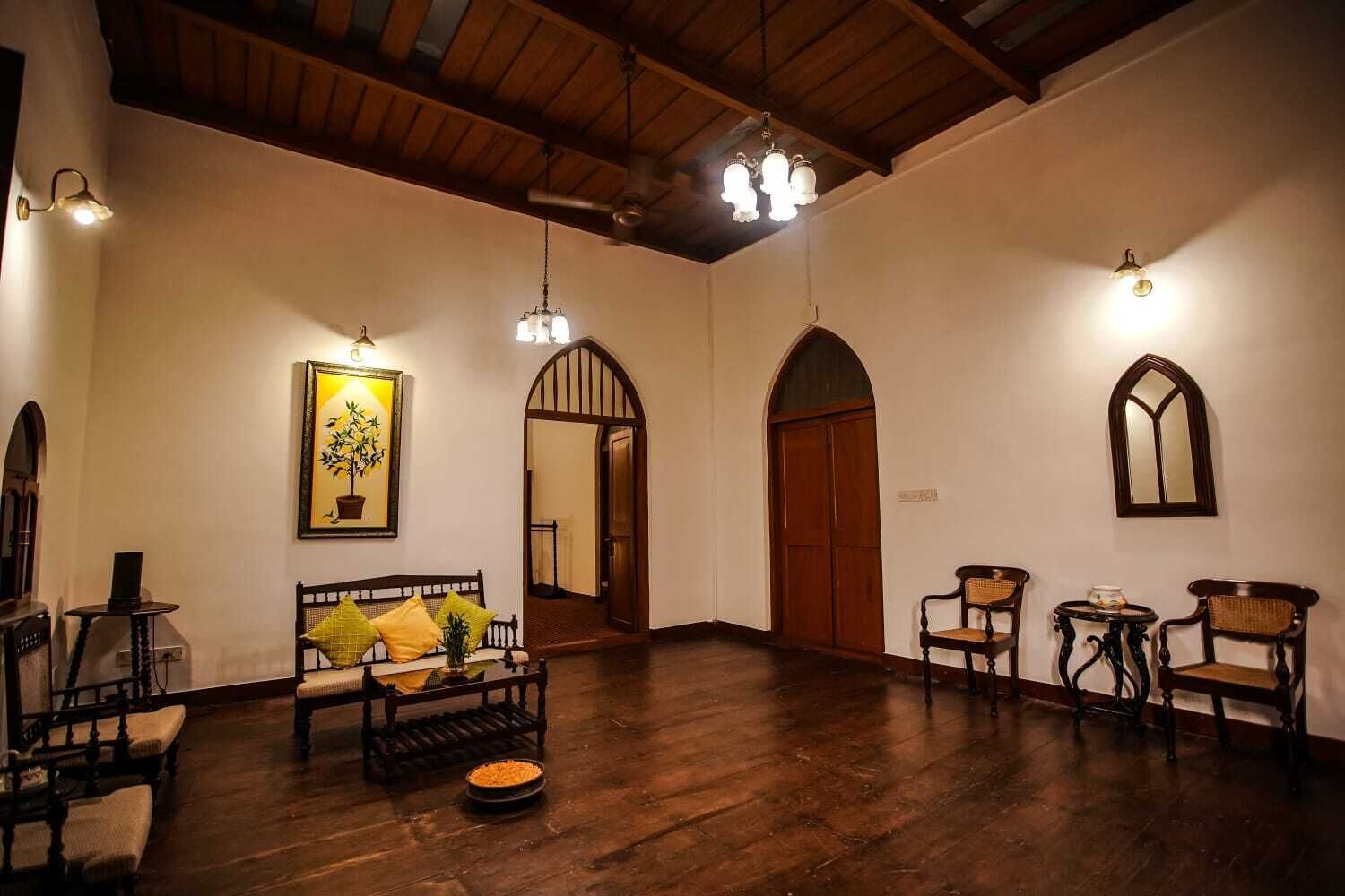 Una habitación amplia con techo de madera, un sofá con cojines, una mesa de comedor con sillas y un gran arco de entrada.