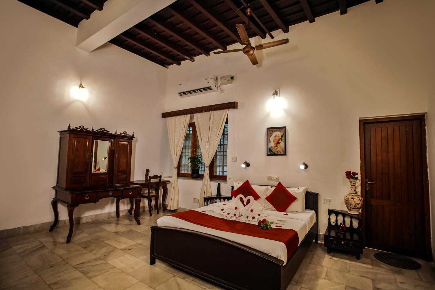 A bedroom with a bed, a wooden dresser, a desk, and a chair.