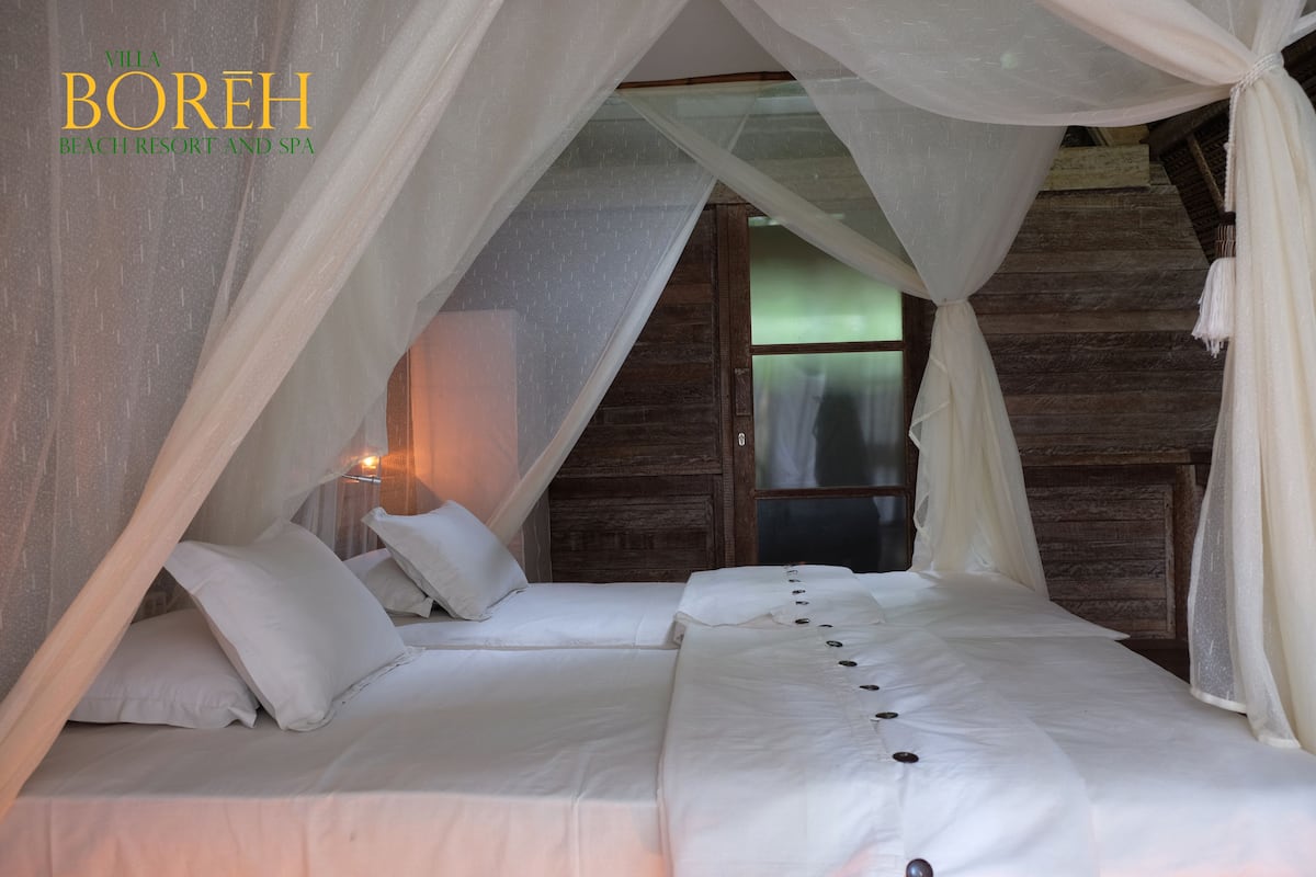A bedroom with a canopy bed, wooden walls, and a window.
