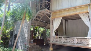 A wooden structure with a bed and a balcony, surrounded by lush greenery. - Villa Boreh Beach Resort and Spa (Tejakula)