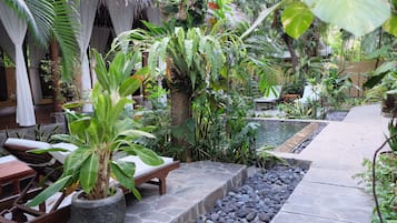 Escape to a serene oasis surrounded by lush tropical plants and a soothing water feature.