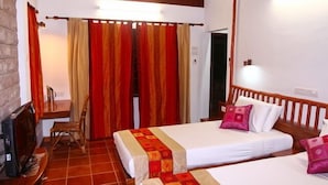 Habitación de hotel con dos camas, cabecero de madera, una mesita con una silla y una chimenea.