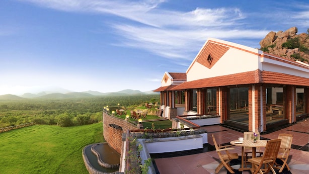 Un hotel con terraza y vistas a un paisaje verde exuberante y montañas lejanas.