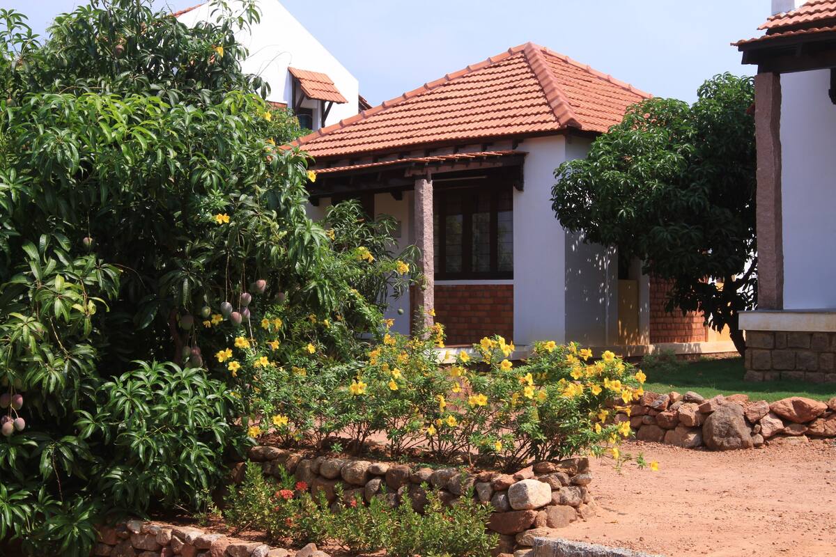 Ein Haus mit rotem Ziegeldach, umgeben von üppigem Grün und gelben Blumen.