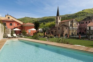 Una piscina al aire libre, sombrillas, sillones reclinables de piscina
