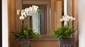 A hallway with a console table holding two potted plants and a lantern. - Relais Del Maro (Borgomaro)