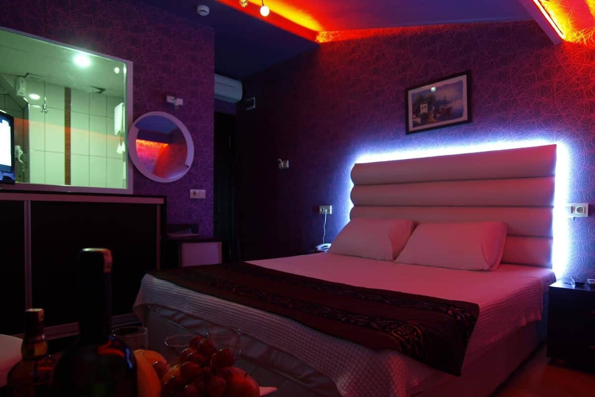 Ein modernes Schlafzimmer mit einem großen Bett, einem Nachttisch, einem Spiegel und einem Wandbild.