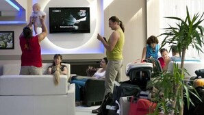 A modern hotel lobby with a flat-screen TV mounted on the wall, a white sofa, and a potted plant. - Timya Hotel (Istanbul)