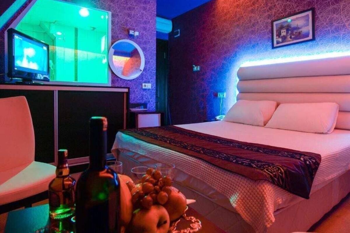 Ein modernes Hotelzimmer mit einem großen Bett, einem Schreibtisch mit Stuhl, einem Fernseher und einem Wandspiegel.