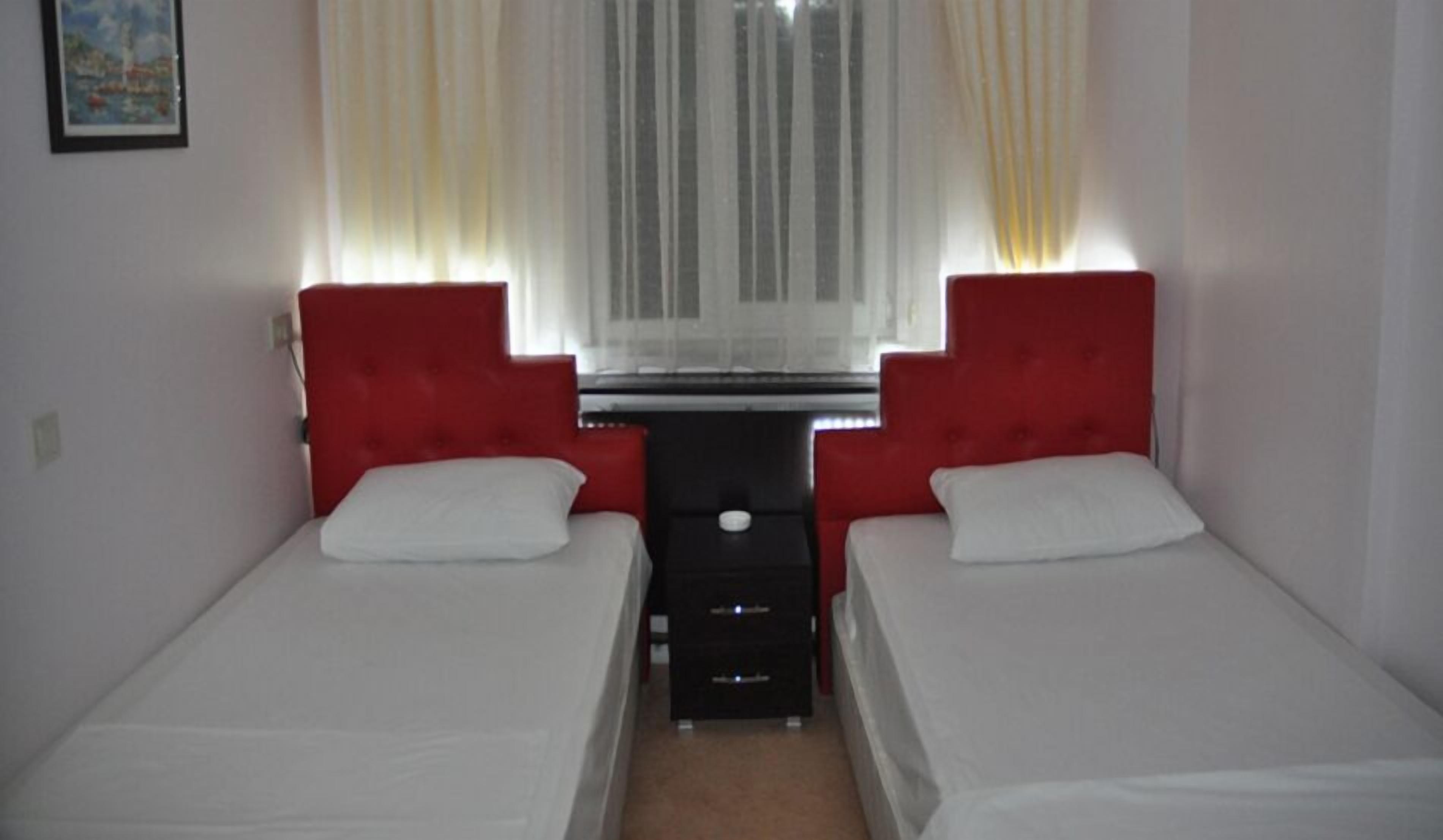 A room with two single beds, a small table, and a window with curtains.