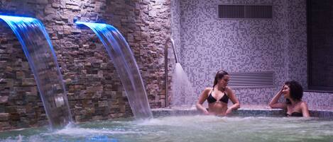 A spa area with a stone wall and two waterfalls.