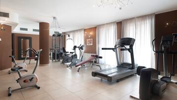 A modern gym with various cardio and strength training equipment, including treadmills, elliptical machines, and weight machines.