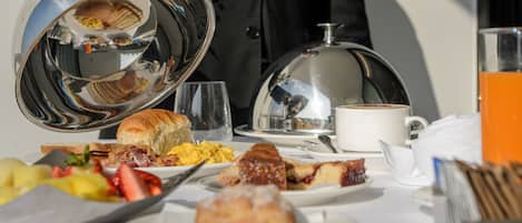 Ein reichhaltiges Frühstücksbuffet mit verschiedenen Speisen, einer Kaffeekanne und einem Glas Orangensaft.