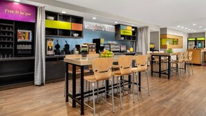 A modern restaurant with a bar area, seating, and a counter with a menu display. - Home2 Suites by Hilton Baltimore / Aberdeen, MD (Aberdeen)