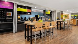A modern restaurant with a bar area, seating, and a counter with a menu display. - Home2 Suites by Hilton Baltimore / Aberdeen, MD (Aberdeen)