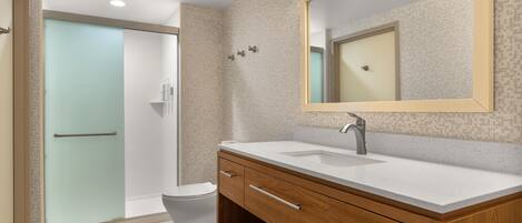 A modern bathroom with a wooden vanity, a large mirror, and a glass shower enclosure.