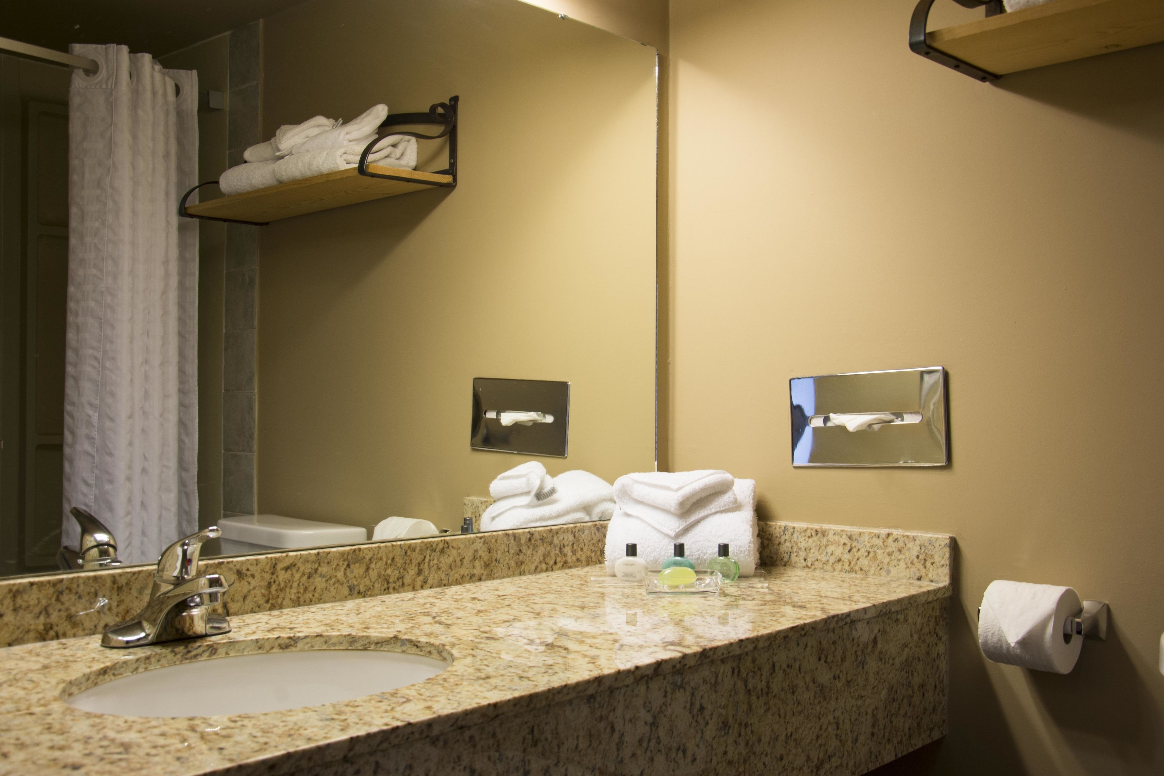A bathroom with a granite countertop, a sink, a mirror, and a towel rack.