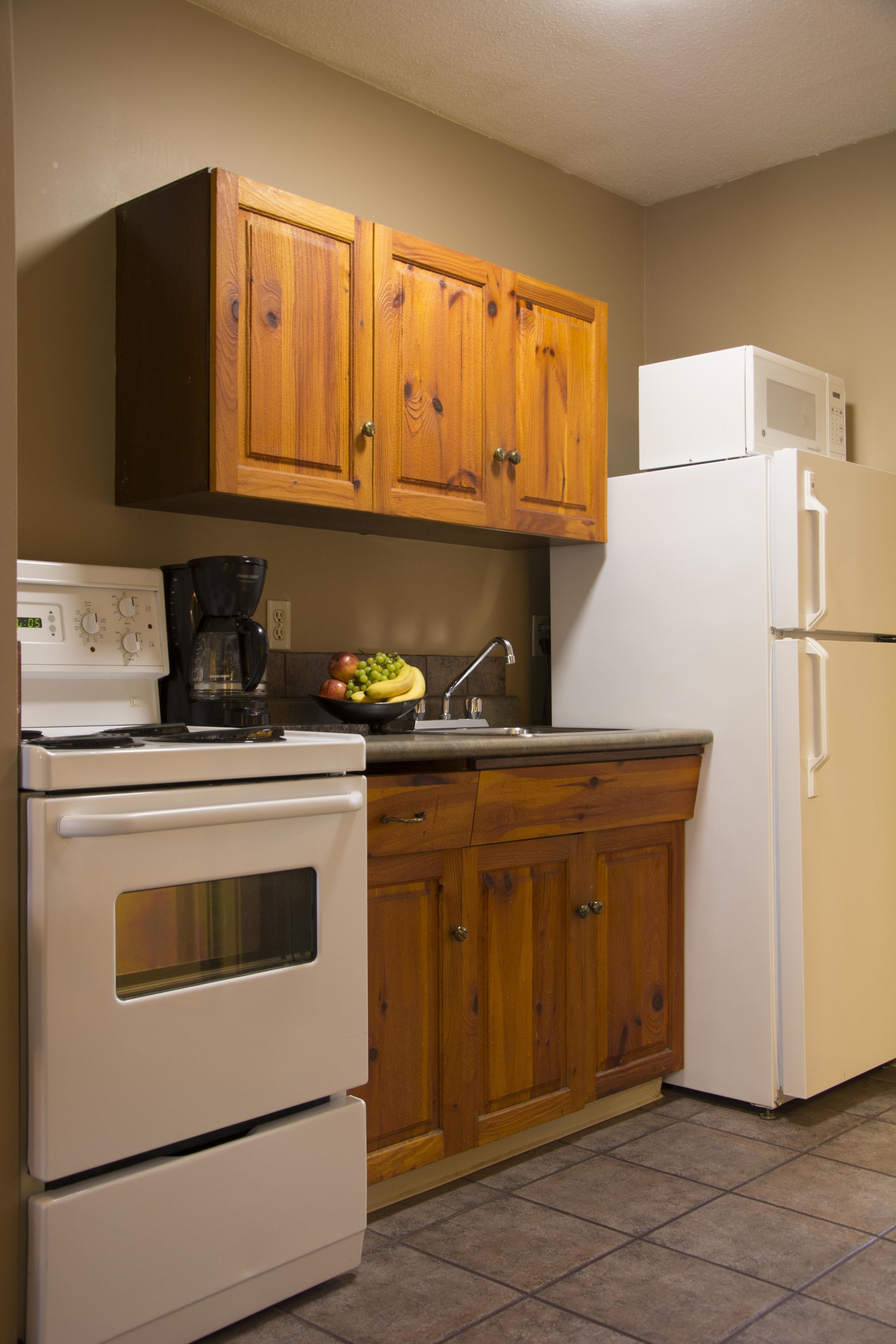 A kitchen with wooden cabinets, a white stove, a white refrigerator, and a coffee maker.