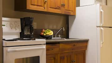 Una cocina con armarios de madera, una estufa blanca, un refrigerador blanco y una cafetera.