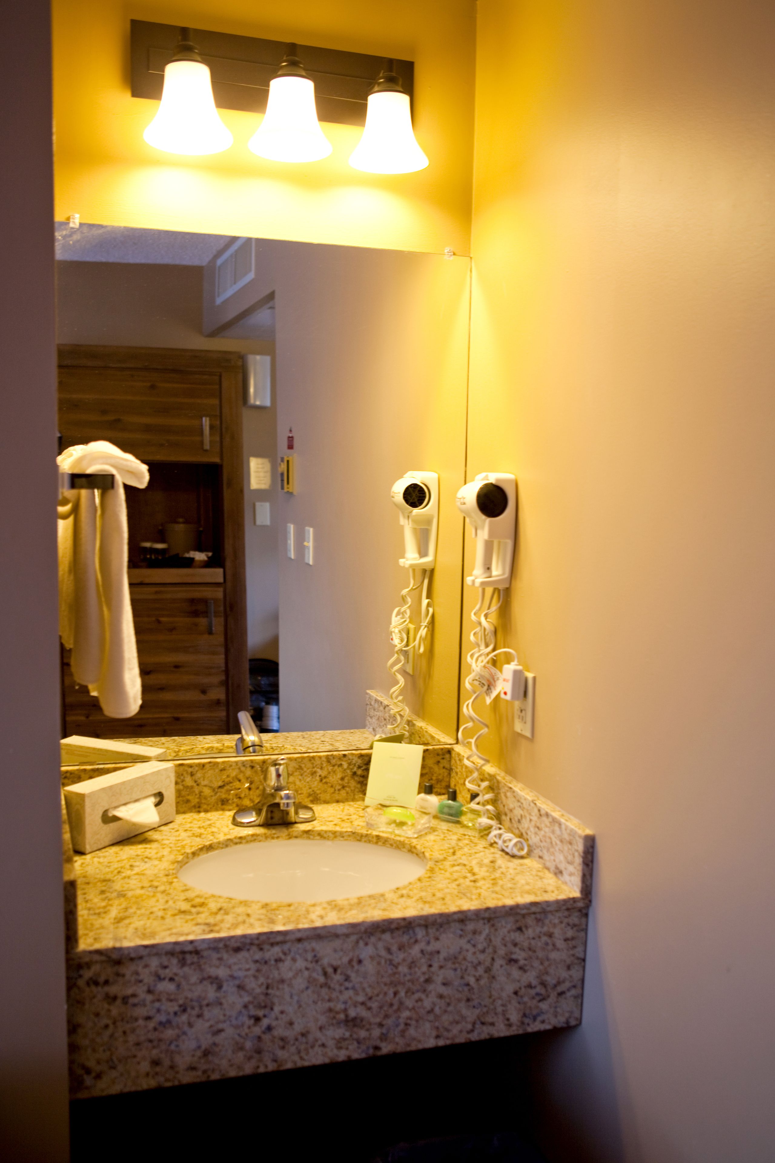 A bathroom with a sink, mirror, towel rack, and hairdryer.