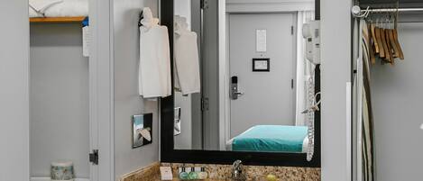 A bathroom with a granite countertop, a sink, a mirror, and a towel rack.