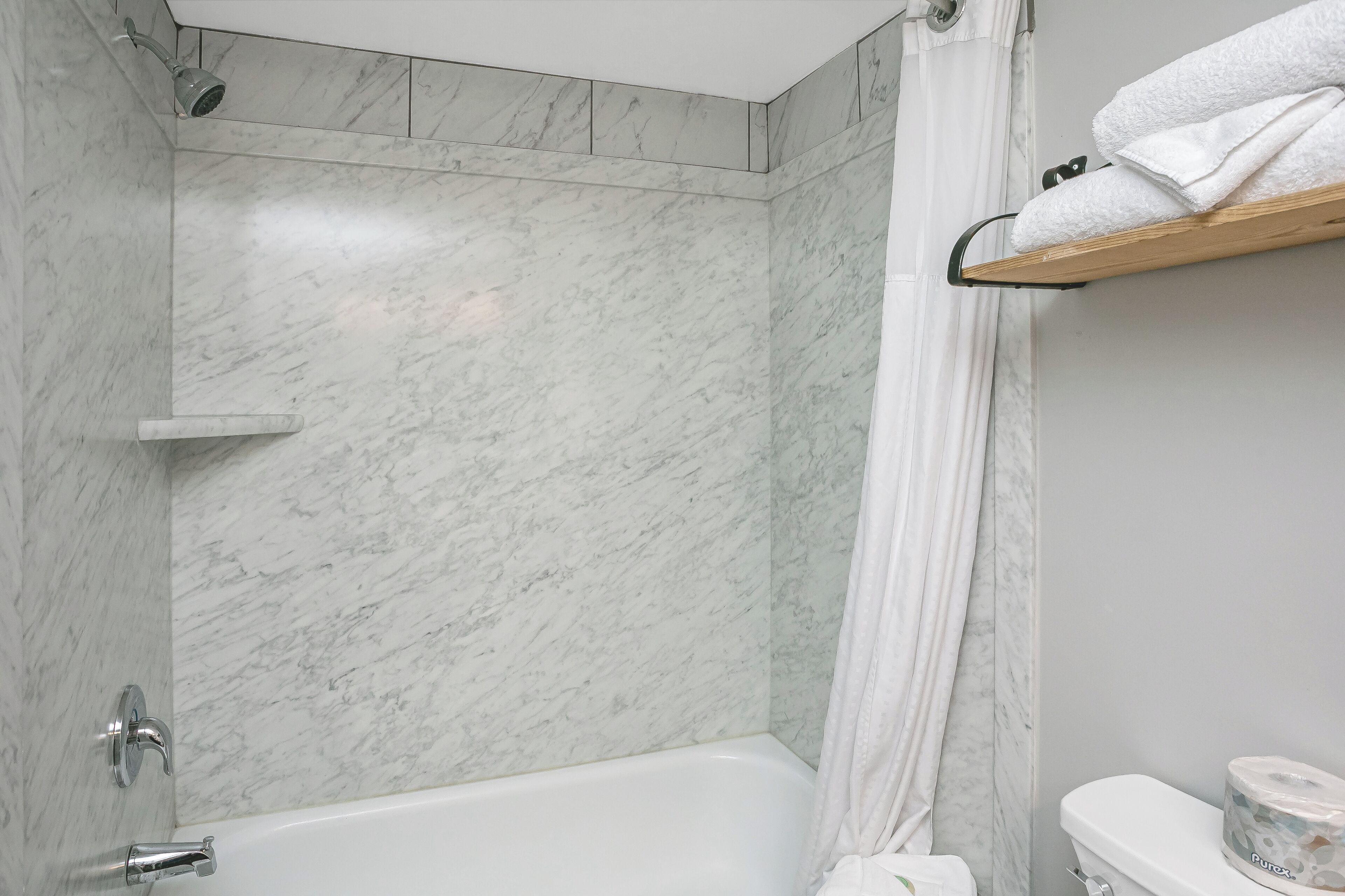 Une salle de bain avec une douche, des toilettes et un porte-serviettes.
