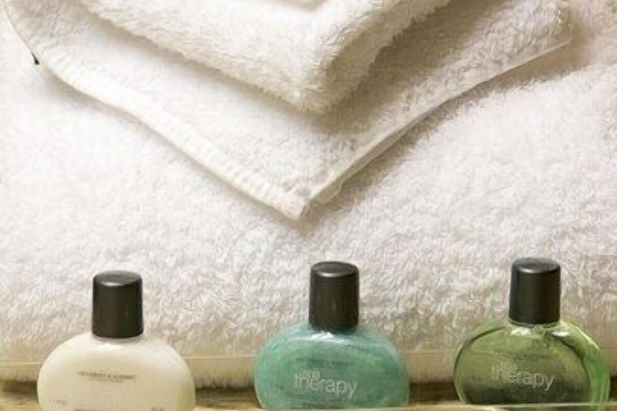 Three bottles of liquid soap on a countertop with a folded white towel in the background.