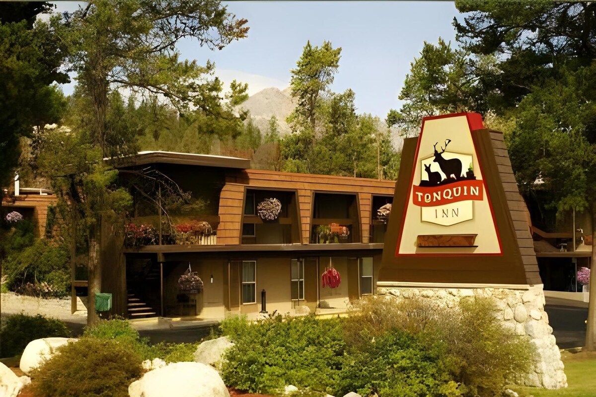 A lodge with a prominent sign, a multi-story building with balconies, and a landscaped garden.