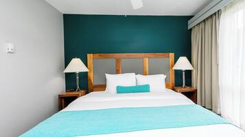 Un lit bien fait, avec une tête de lit en bois, deux tables de chevet avec des lampes et un coussin décoratif de couleur turquoise.