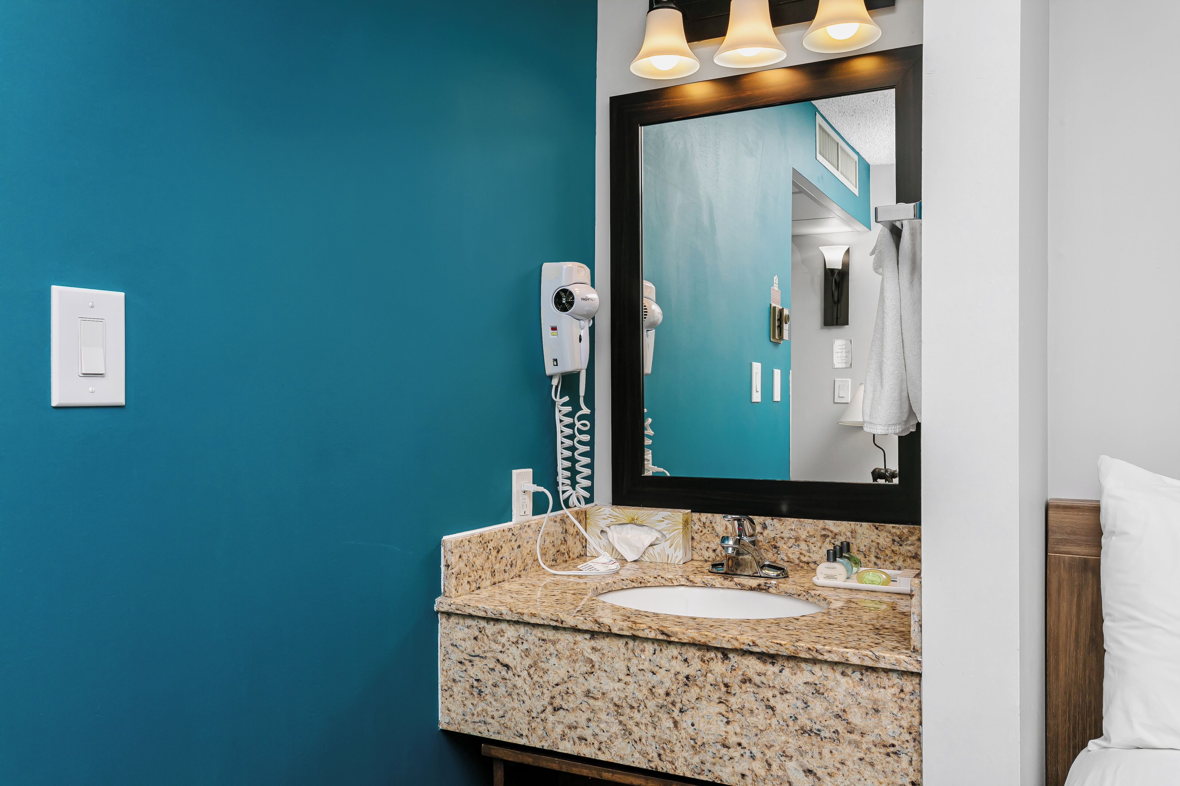A bathroom with a blue wall, a white sink, a mirror, and a towel rack.