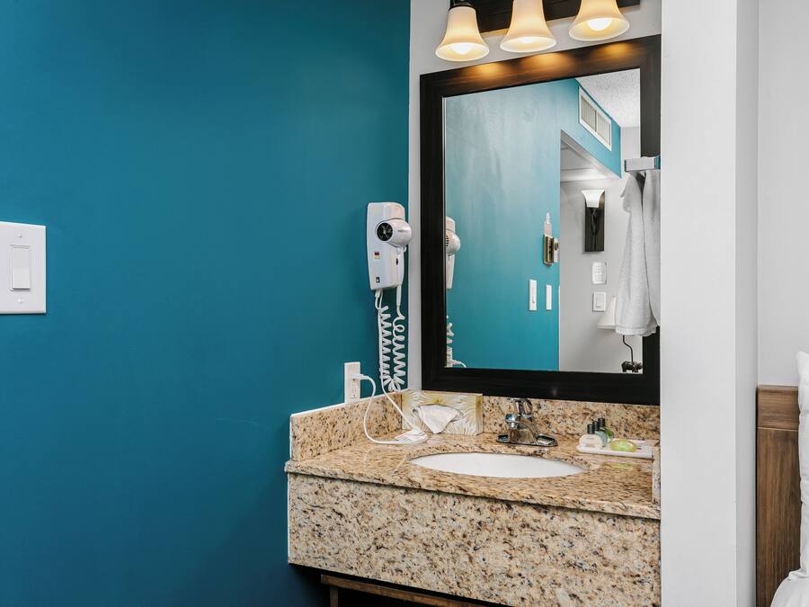A bathroom with a blue wall, a white sink, a mirror, and a towel rack.