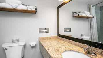 A bathroom with a toilet, sink, mirror, towel rack, and a roll of toilet paper.