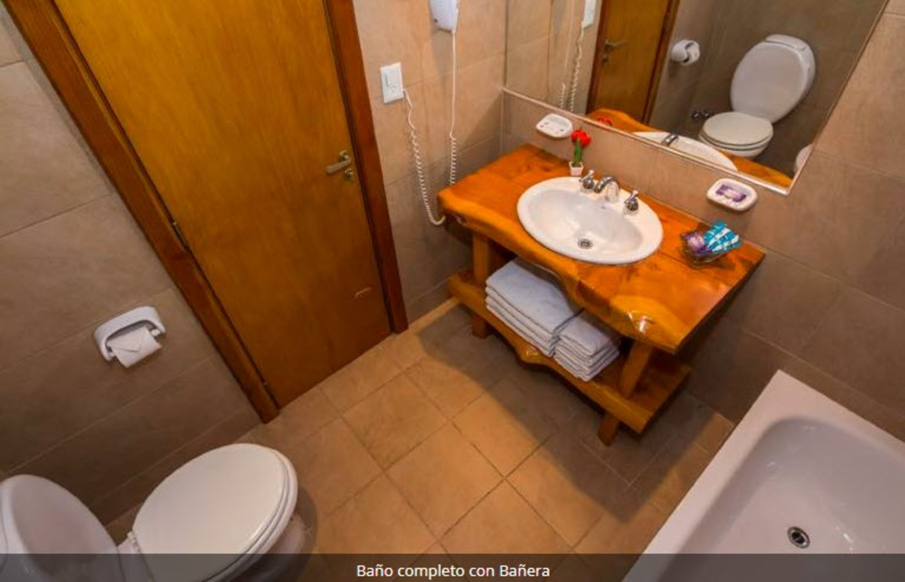 A bathroom with a wooden vanity, a sink, a mirror, a toilet, and a bathtub.