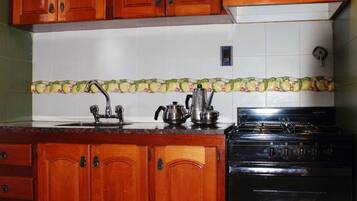 Una cocina con armarios de madera, una estufa negra y un respuesto de azulejos.