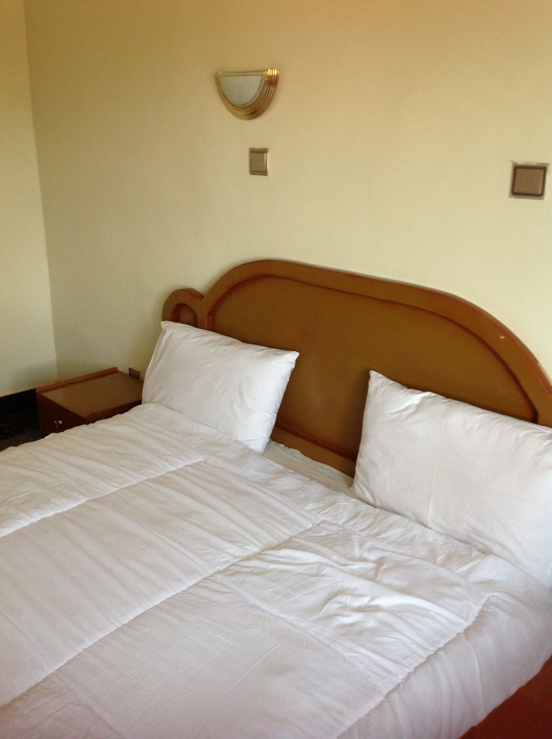 Una cama bien hecha con sábanas blancas en una habitación de hotel.