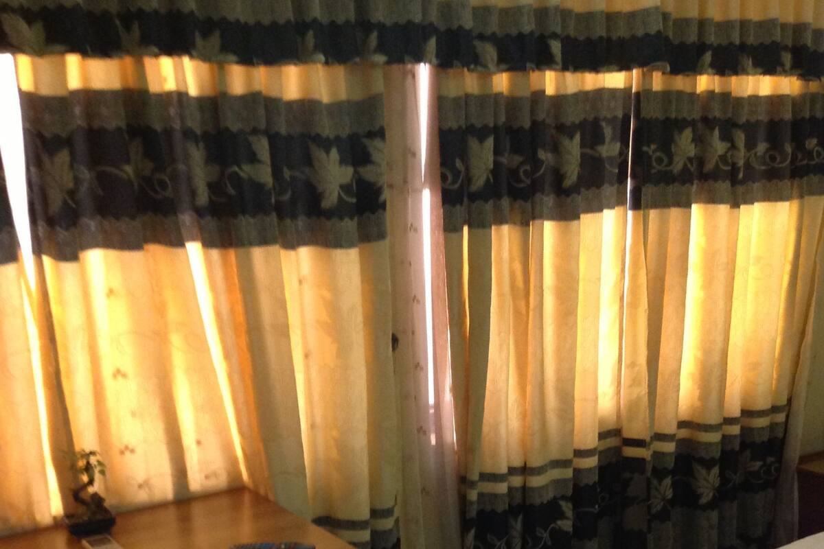 A hotel room with a bed, a desk, and curtains.