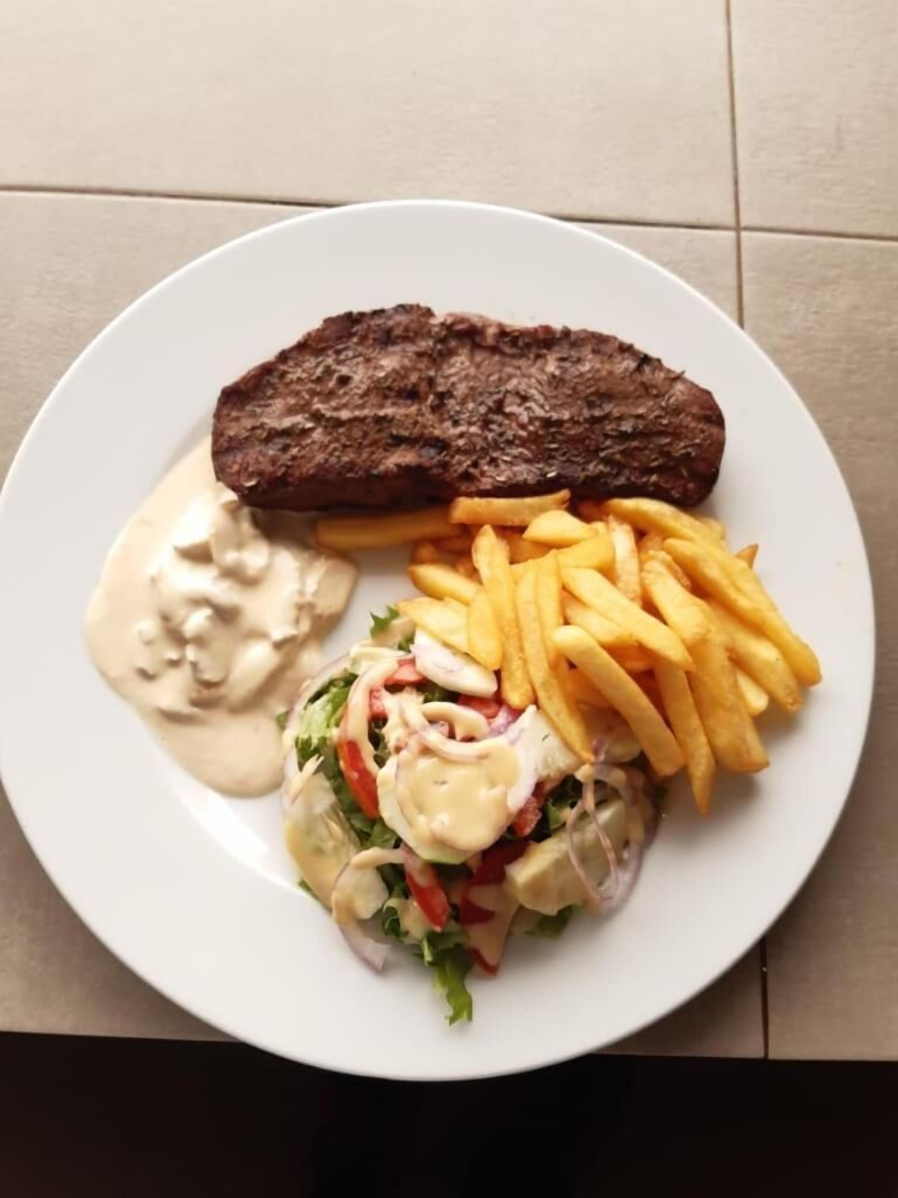 A plate with a steak, fries, and a salad.