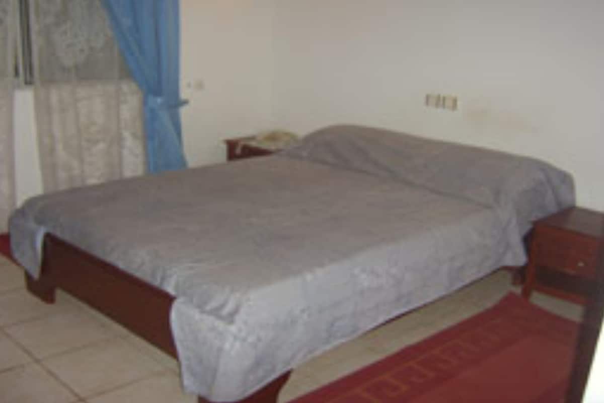 A bedroom with a bed, a nightstand, and a small table.