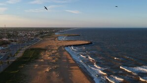 Een kustgebied met een zandstrand, een boulevard en uitzicht op zee.