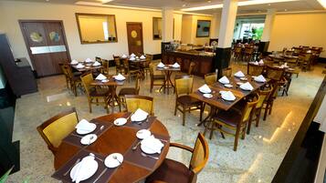 Un comedor amplio con varias mesas y sillas, un mostrador de buffet y un ambiente bien iluminado.