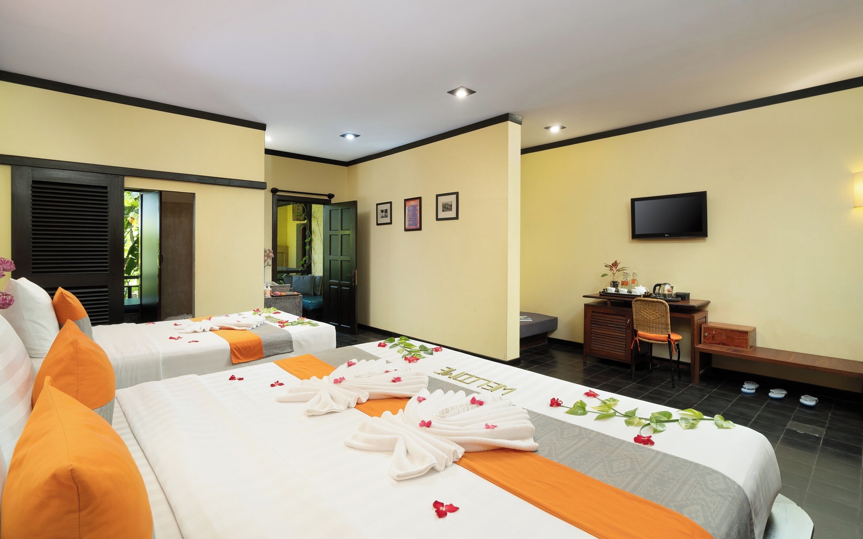 A hotel room with two beds, a desk, a television, and a bathroom.