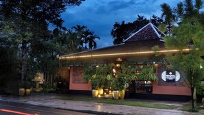 Un edificio con techo tradicional, rodeado de abundante vegetación y una entrada bien iluminada.