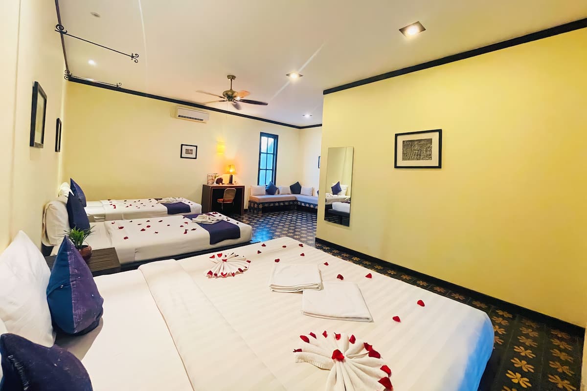 Ein Hotelzimmer mit zwei Betten, einem Schreibtisch, einem Stuhl, einem Deckenventilator und einem großen Fenster.