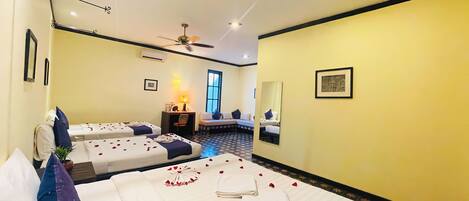 A hotel room with two beds, a desk, a chair, a ceiling fan, and a large window.