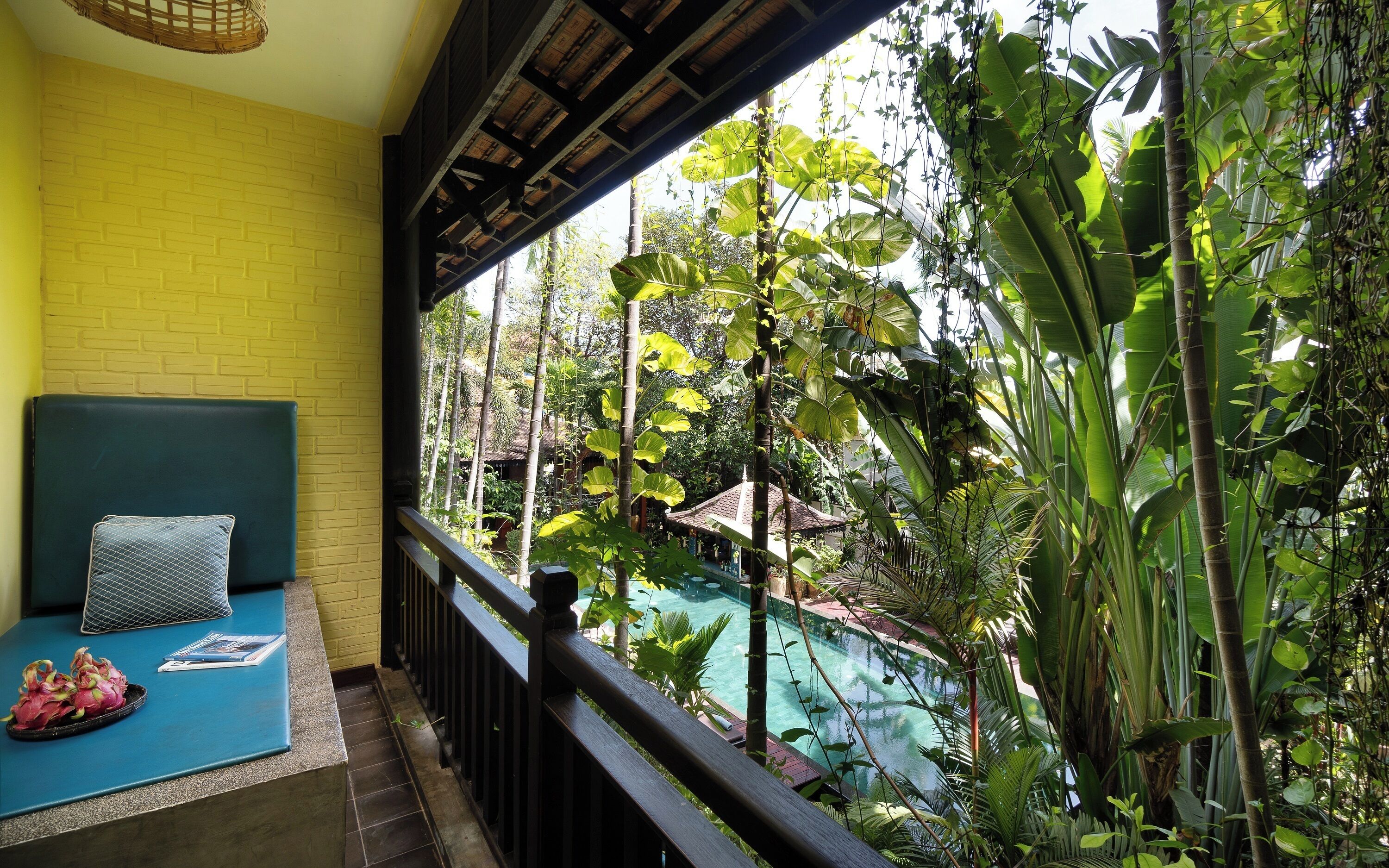Un balcon donnant sur une piscine entourée d’une végétation luxuriante.
