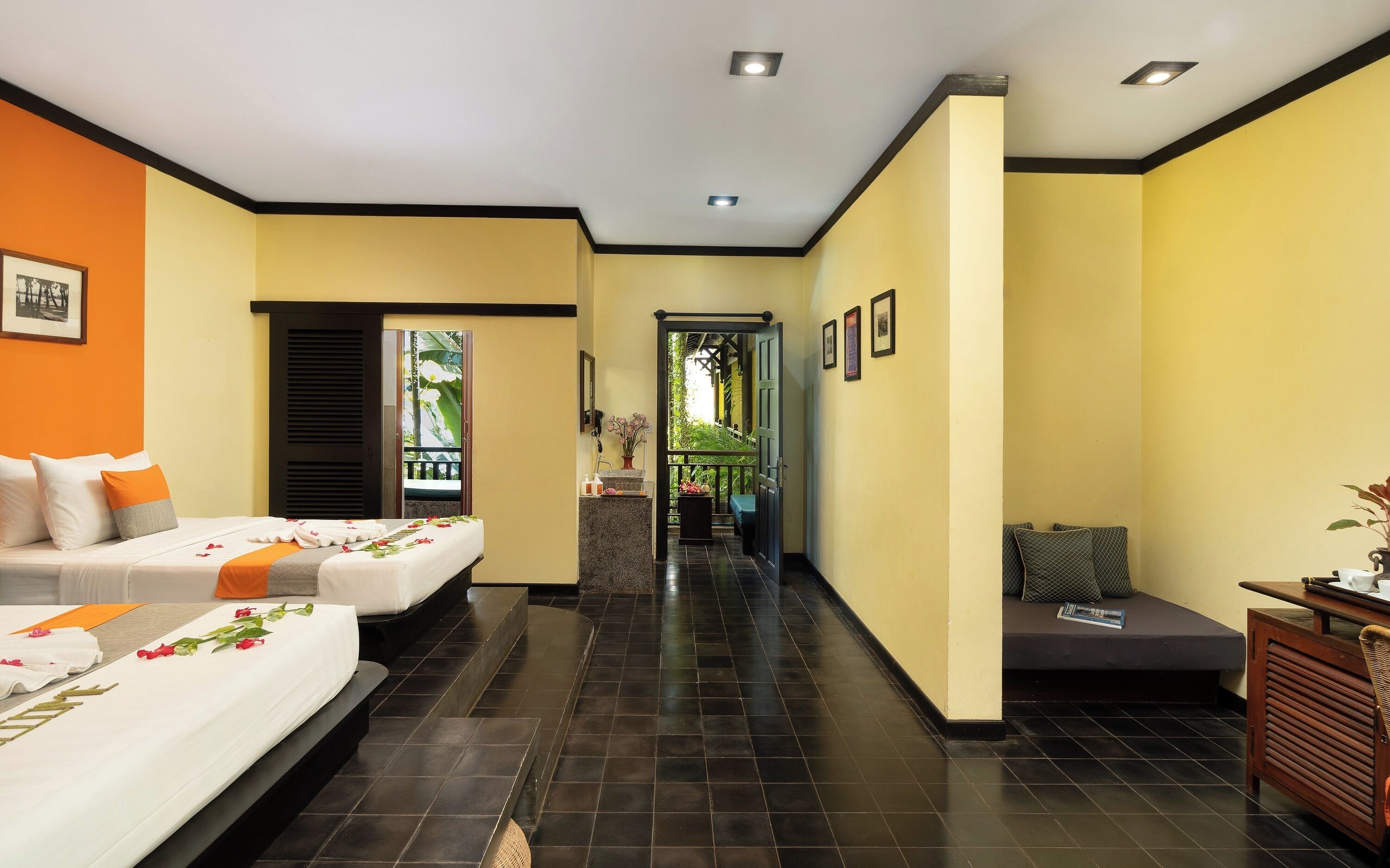 Een hotelkamer met twee bedden, een zithoekje en uitzicht op een balkon.