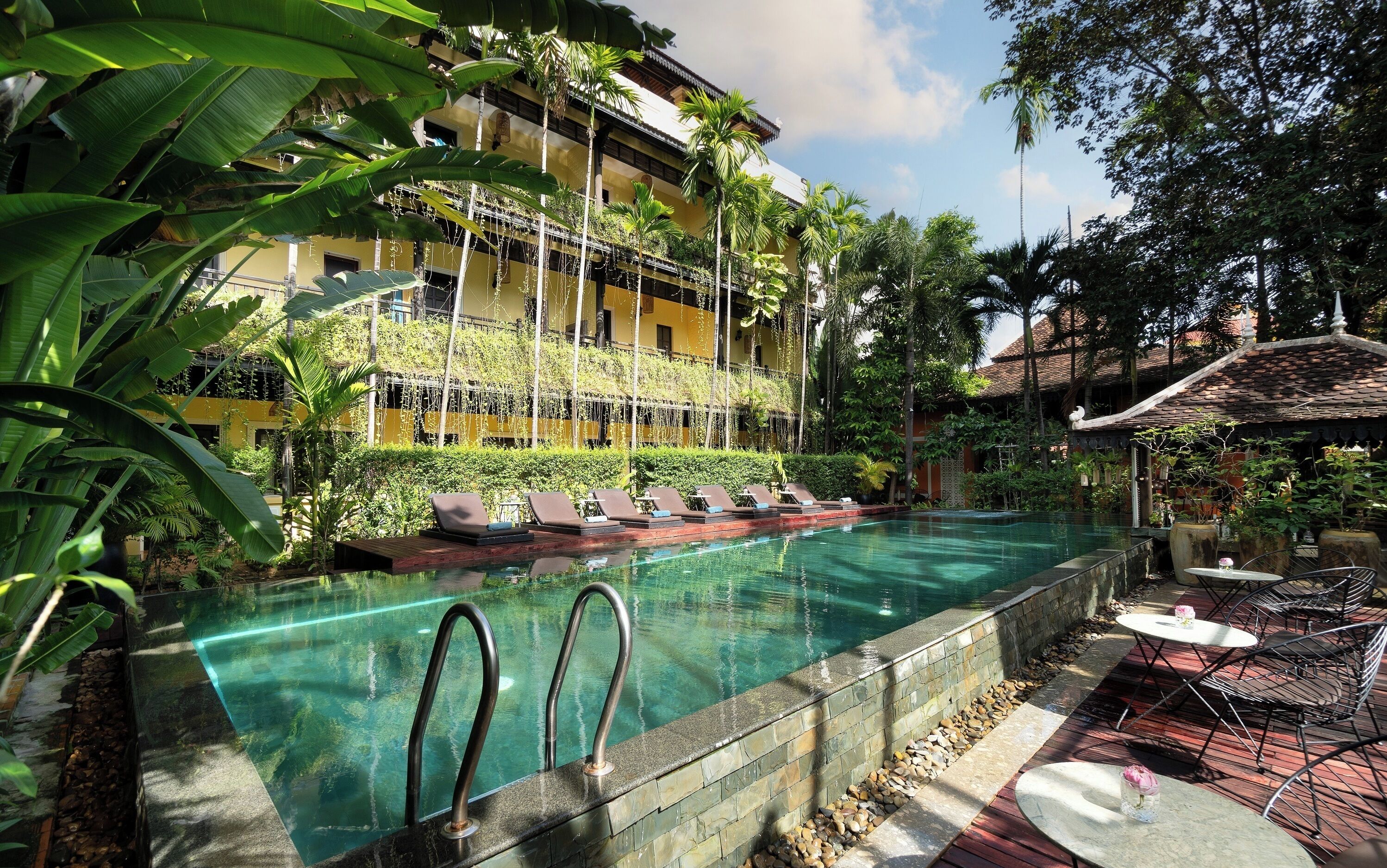 A pool area with lounge chairs and a building with balconies.
